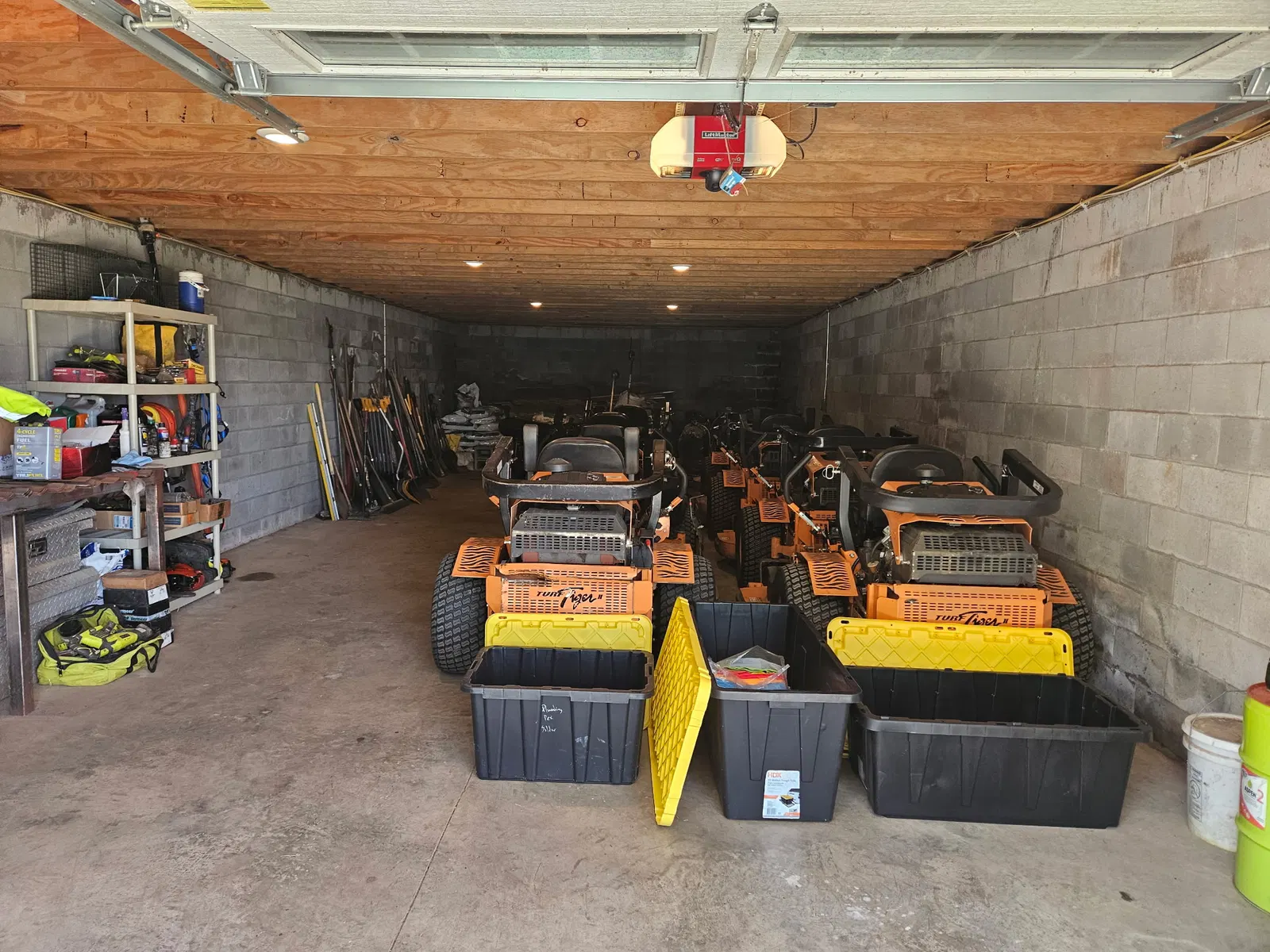 Commercial lawn mowers and maintenance equipment stored inside a garage