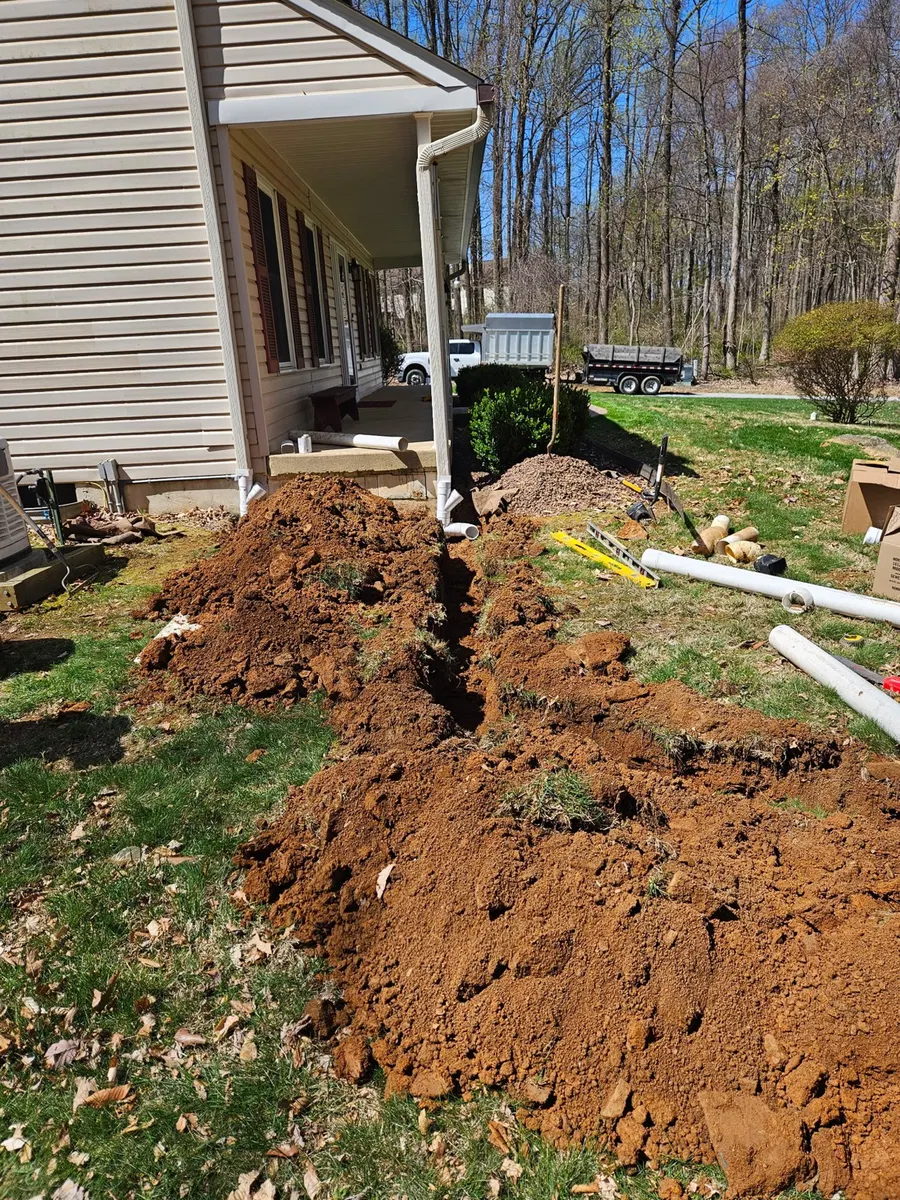 Open drainage trench extending from a downspout beside a home