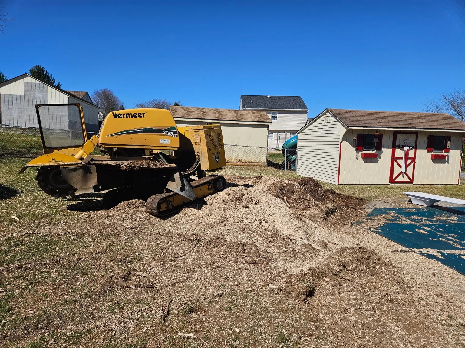 Stump grinder beside a mound of wood chips in a residential yard