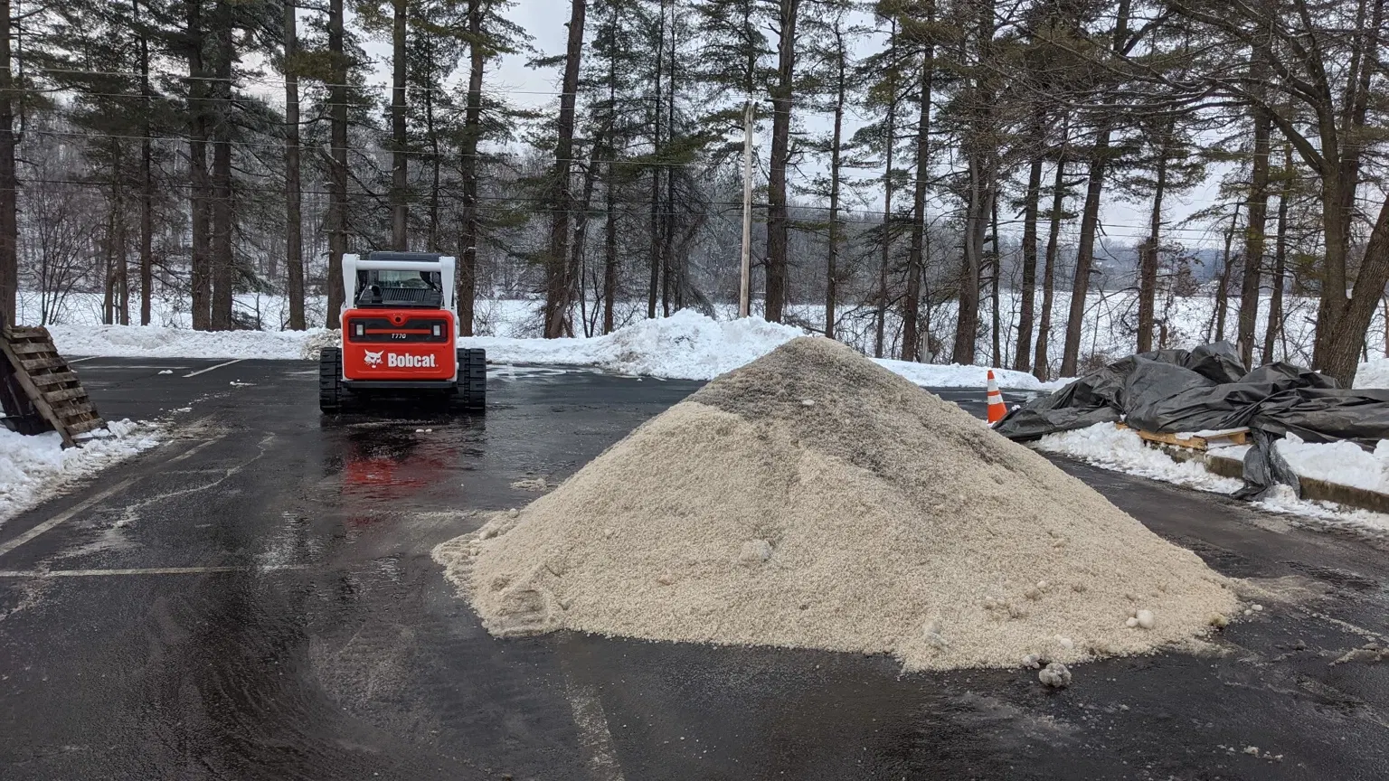 Loader beside a stockpile of winter service material on a paved area
