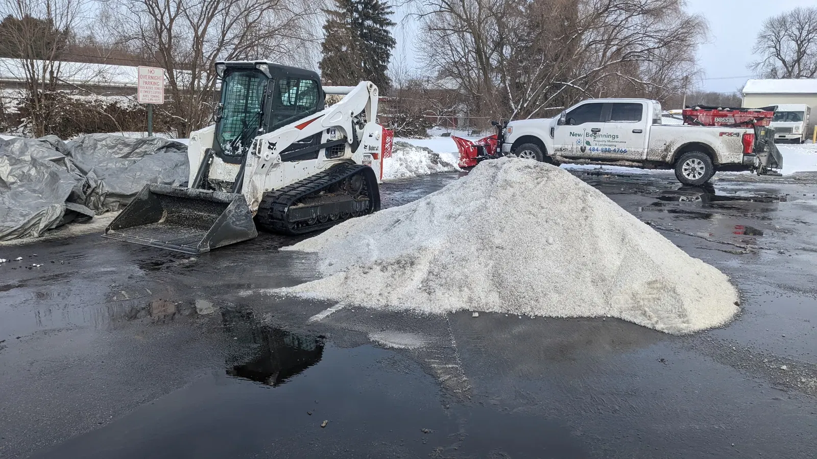 Tracked loader and New Beginnings pickup beside snow and a material stockpile