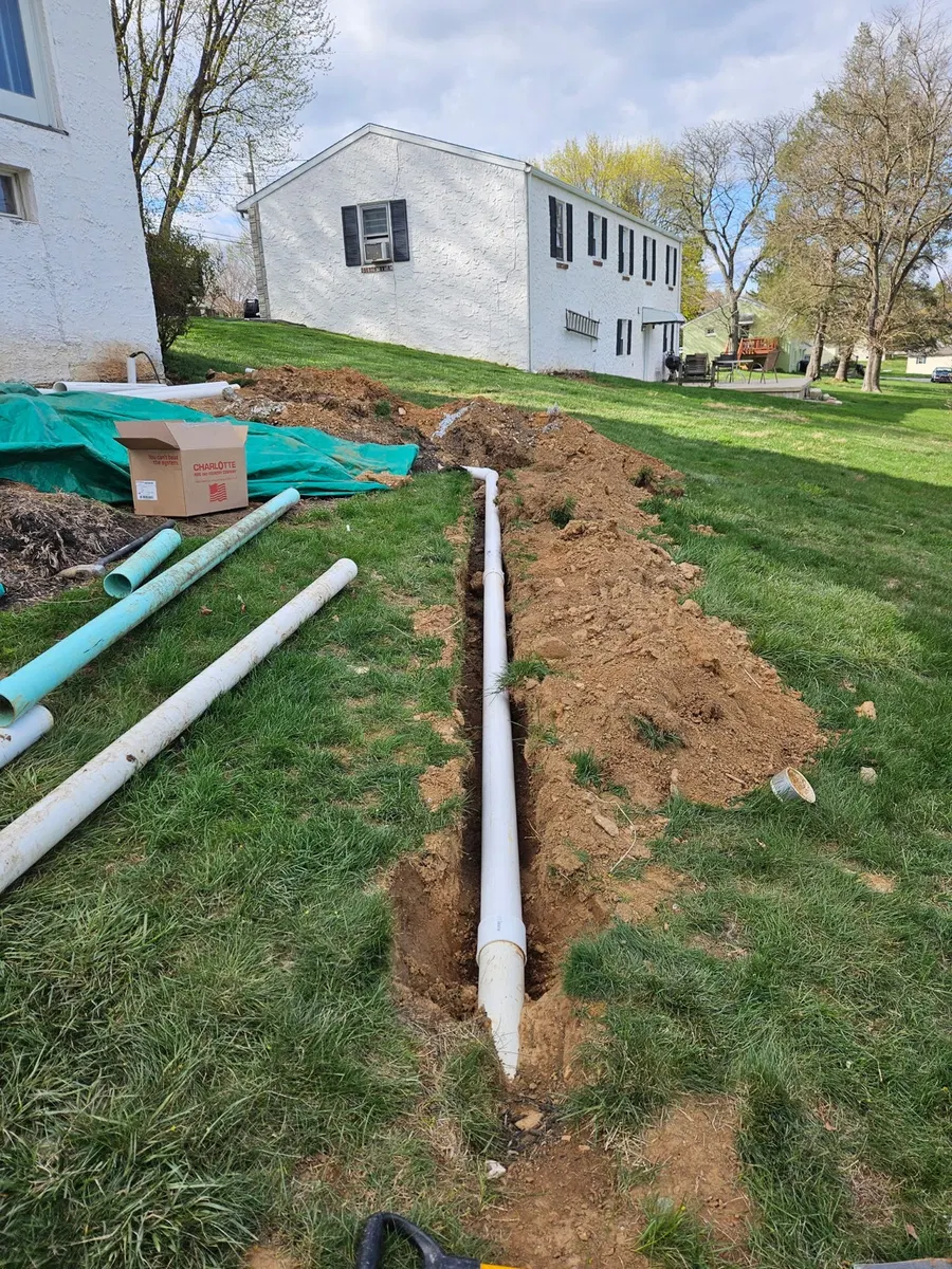 Drainage pipe laid in an open trench across a residential yard